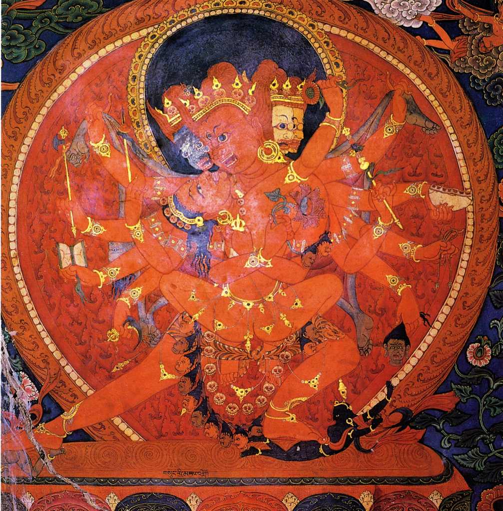 Tibet Guge 09 Tsaparang Demchog Temple 04 Vag Dakini Chakrasamvara Along the left wall is the cycle of Demchog (Skt. Chakrasamvara), with five dakinis each holding Demchog in tantric yab-yum, with the far one being the red-skinned Vag Dakini. His two main arms embrace Vag Dakini, one with a vajra, the other a lotus. Vag Dakini�s left hand circle Chakrasamvara�s neck while her right holds a lotus. In his right hands he holds a vajra lasso, a hatchet, a drum, a trident and a chopper. His left hands hold a vajra lasso, a skull full of blood, a noose, the heads of Brahma, and a khatvanga. Photo - Weyer/Aschoff: Tsaparang, Tibets Grosses Geheimnis,